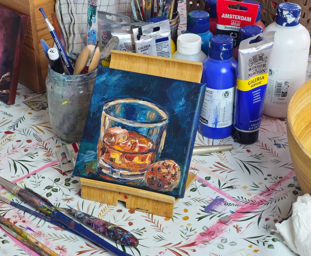 Whiskey Study on a small easel, surrounded by paints and brushes in the studio